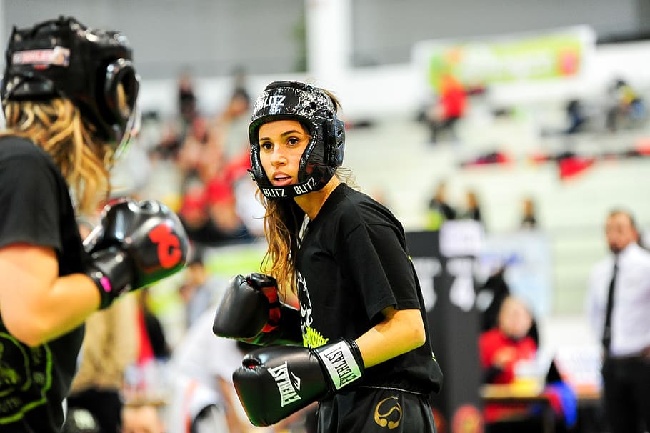 two woman wearing boxing sparing helmet and gloves, martial ates