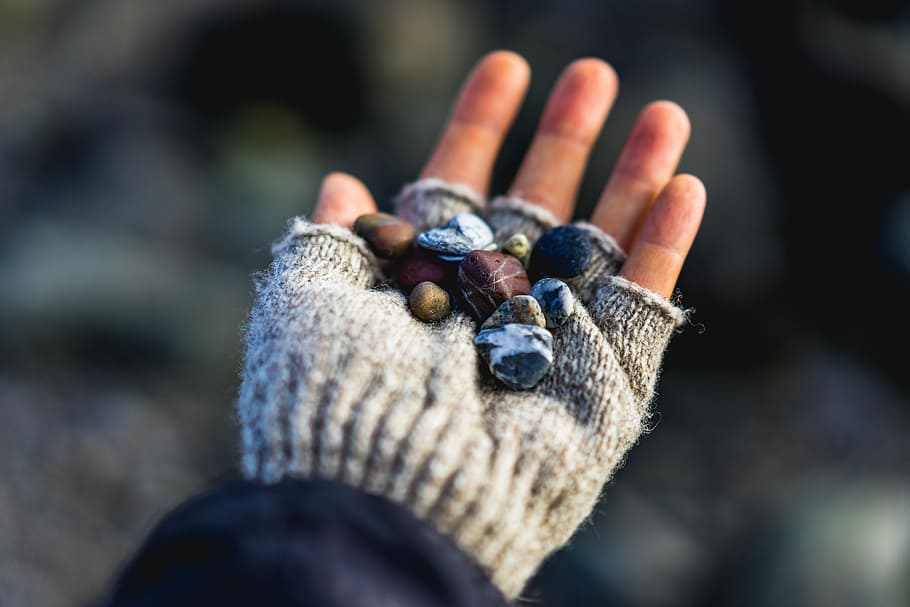 selective focus photo of person wearing gray knit fingerless glove holding stones, person holding stone lot HD wallpaper