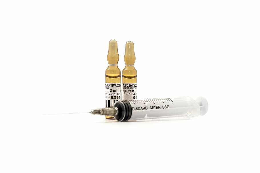 clear syringe with brown glass medication bottles, vaccine, serum