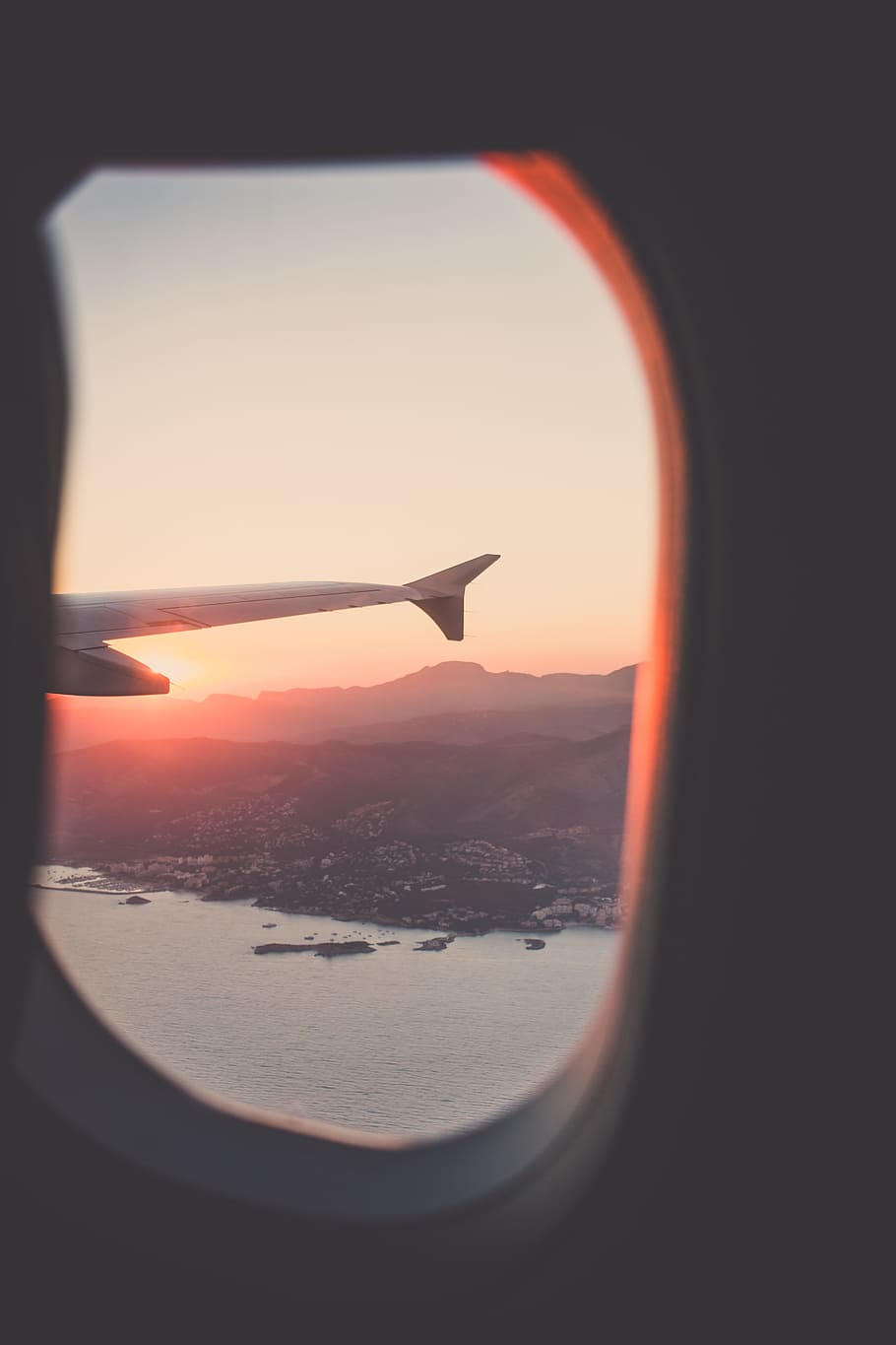 person riding airplane photography, airplane wing through window overlooking island with body of water photography, HD wallpaper