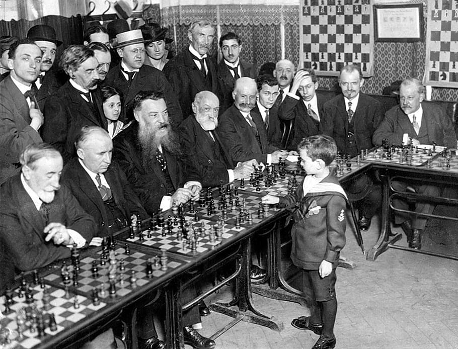 grayscale photo of group of men vs boy playing chess game, chess tournament