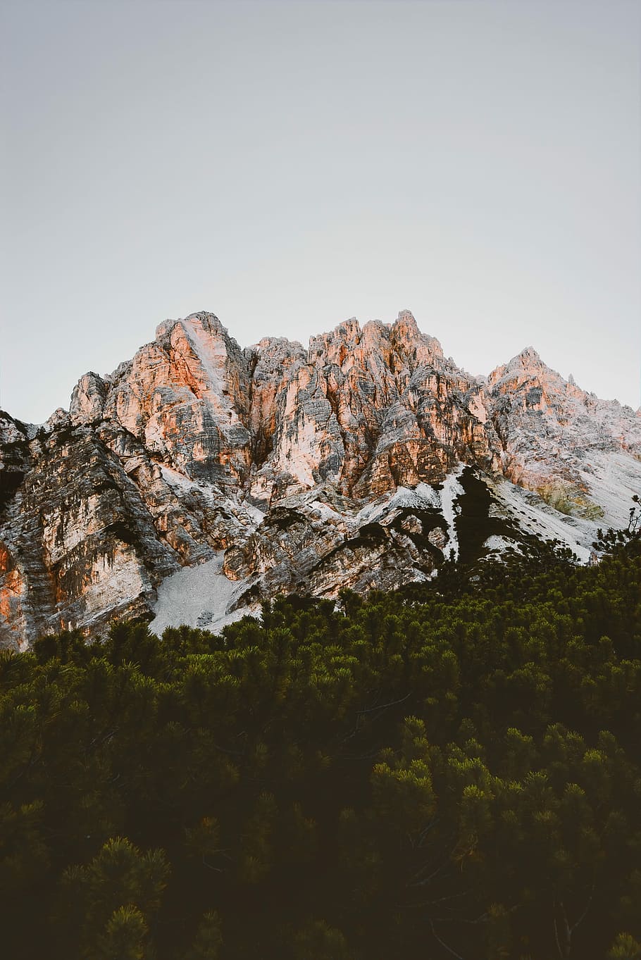 trees below mountain, landscape photography of rocky mountain and green leaf trees under cloudy sky HD wallpaper