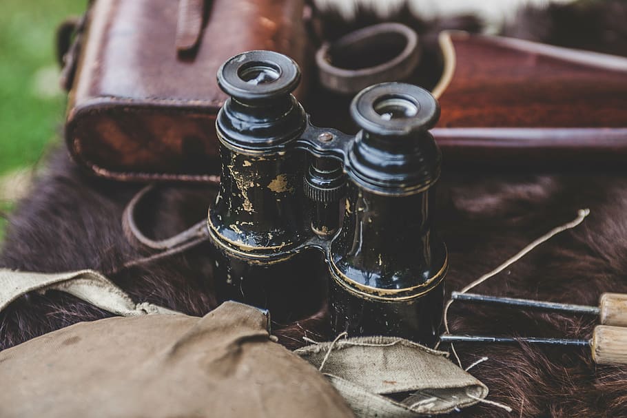 black binoculars on brown fur surface, antique, bottle, closeup