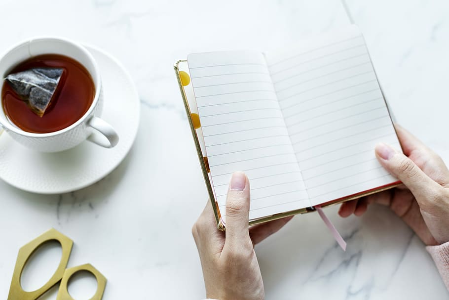 person opening notebook near mug with beverage, tea, cup, plate HD wallpaper