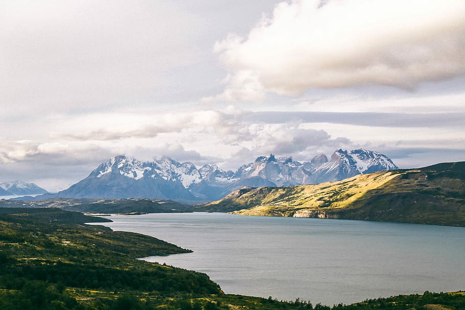aerial view photography of mountain near of river, body of water between mountain under cloudy sky at daytime HD wallpaper