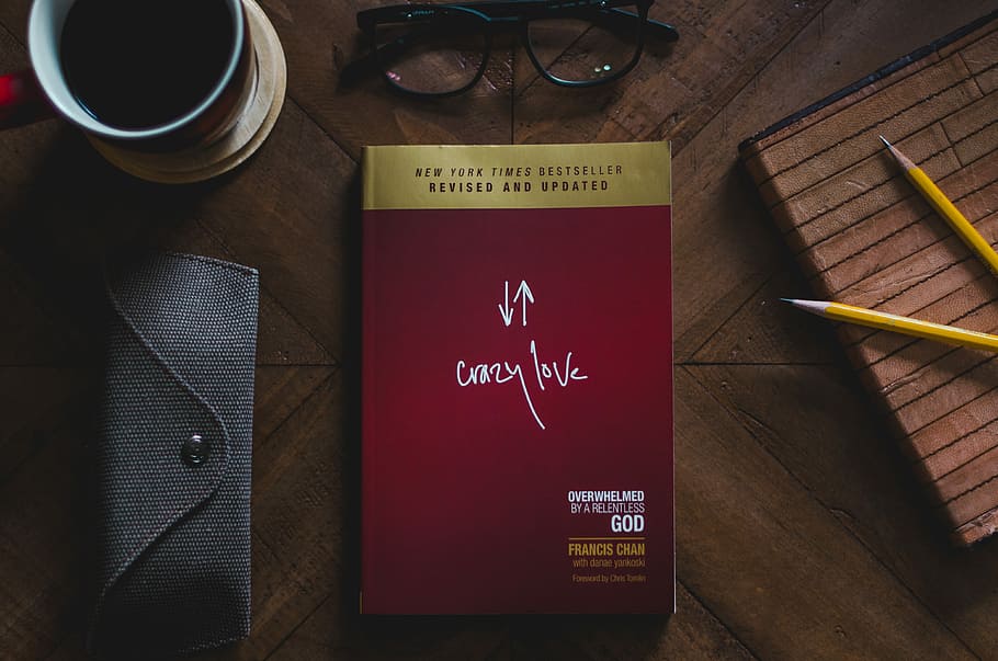 top view photo of Crazy Love book, Crazy Love book beside eyeglasses and two yellow pencils on brown surface HD wallpaper