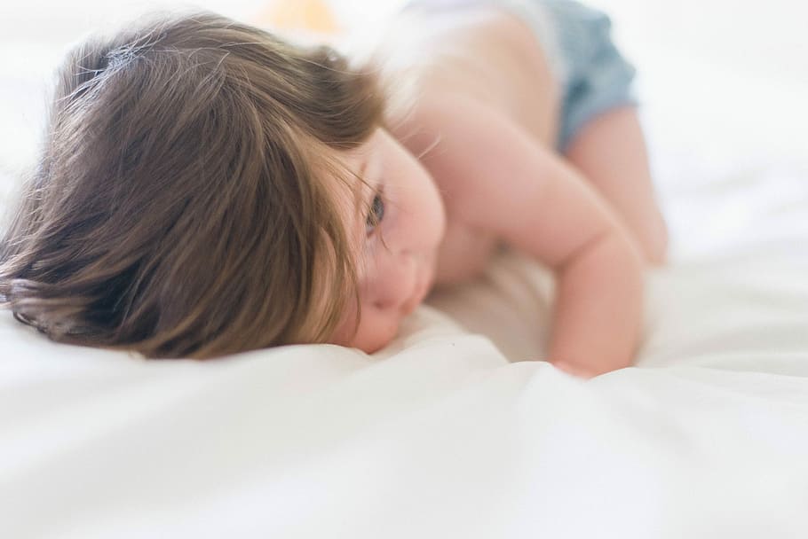 baby laying on white surface, baby wearing blue bottoms lying on white cushion HD wallpaper