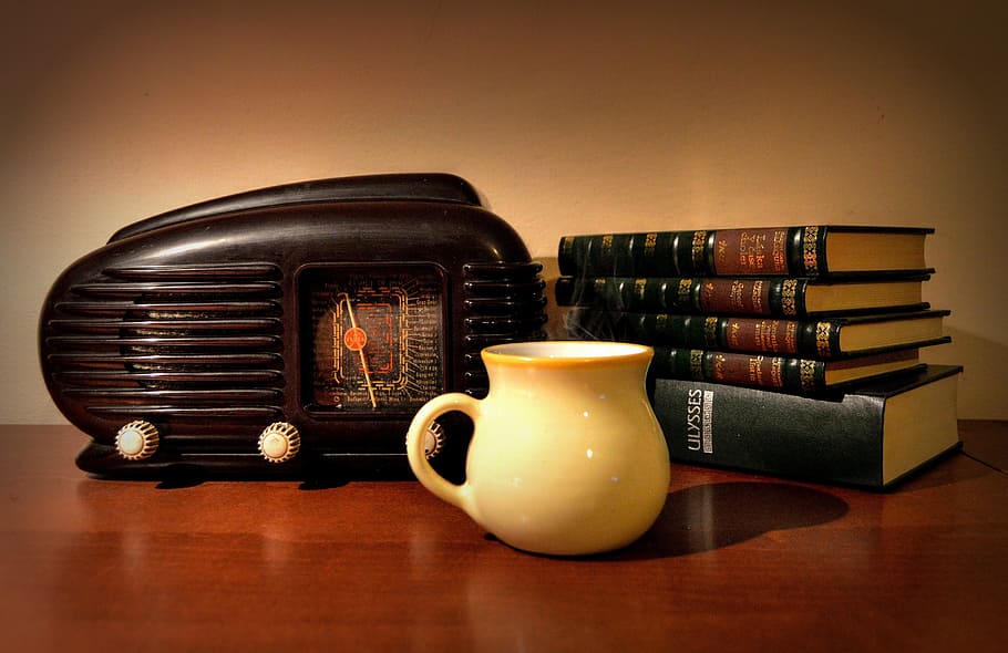 white ceramic coffee cup on brown surface, old, radio, books