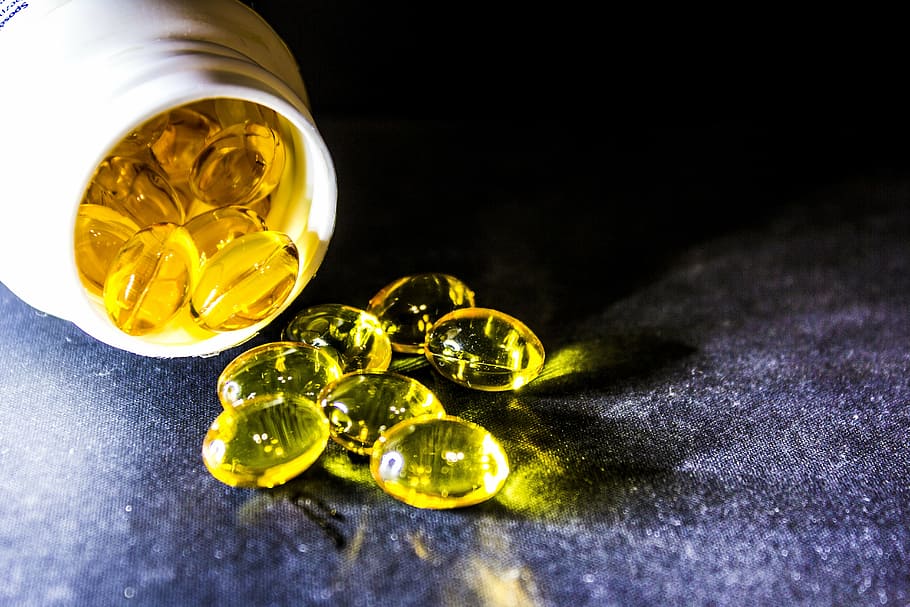 yellow medication pill container spilled on black textile, cure HD wallpaper