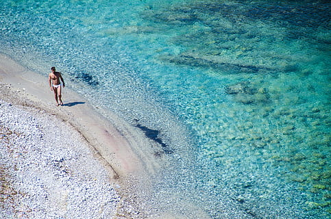 man walking on seashore beside blue se, man standing on shore HD wallpaper