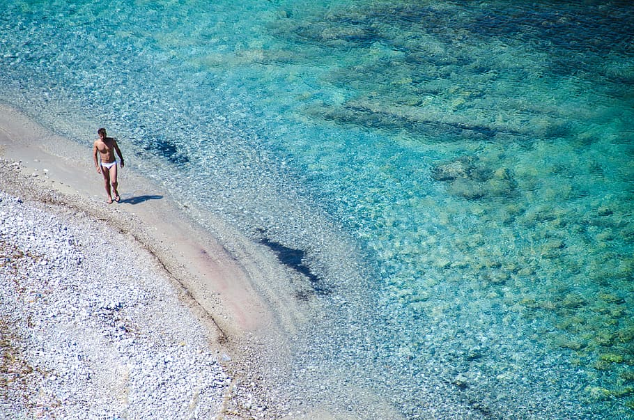man walking on seashore beside blue se, man standing on shore HD wallpaper