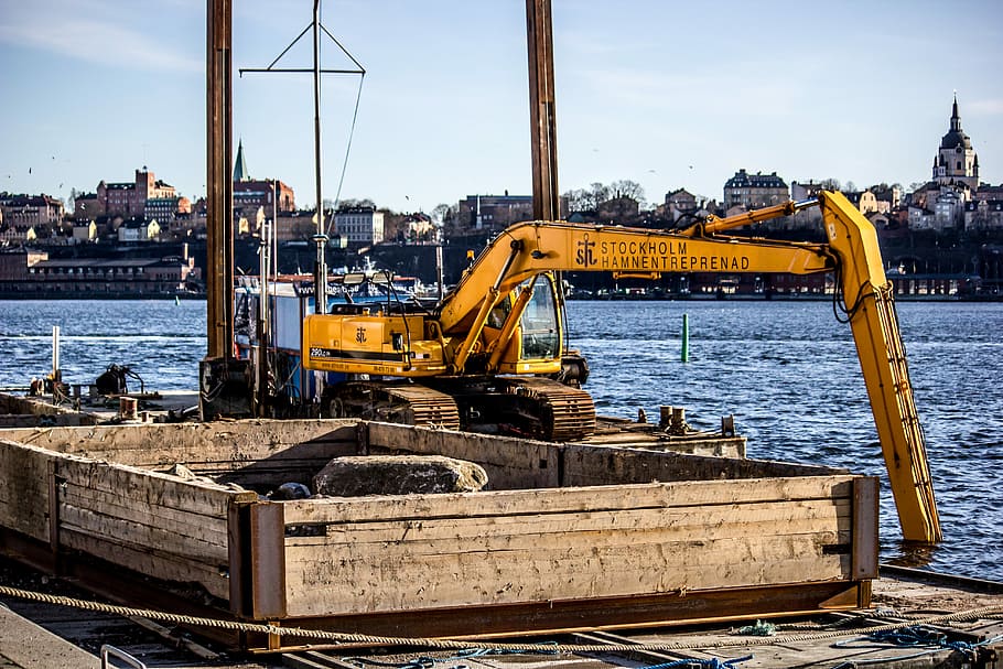 yellow excavator on top of metal platform above sea, yellow crane near body of water HD wallpaper