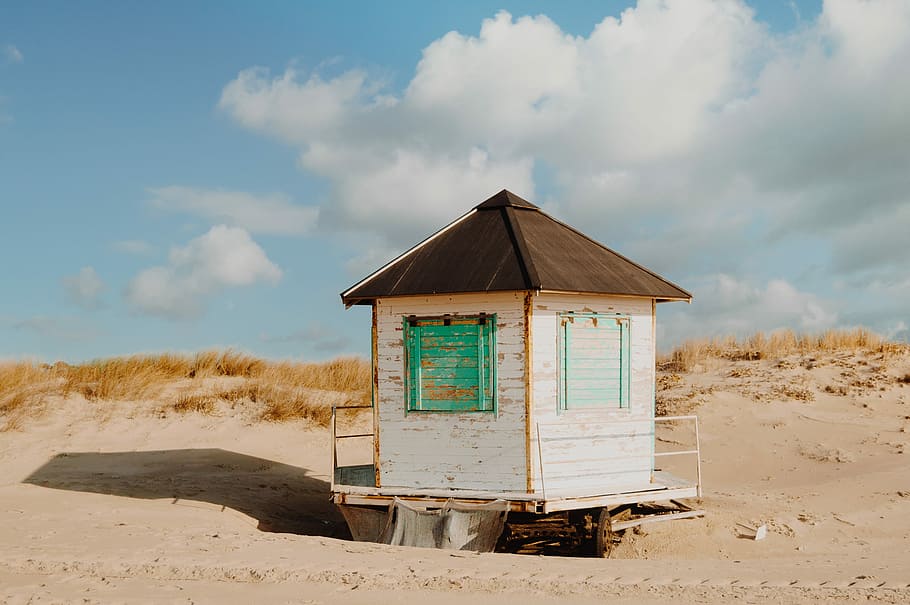 Old hut on a sand beach, white wooden shed near seashore during daytime HD wallpaper