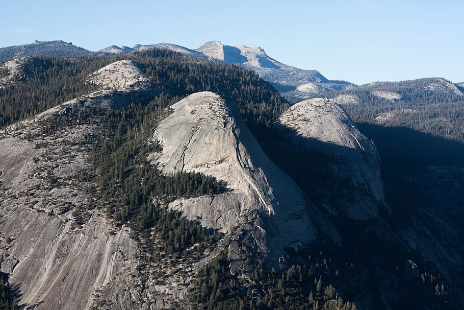 aerial photography of folding mountain with trees at daytime, hills covered with trees under clear sky HD wallpaper
