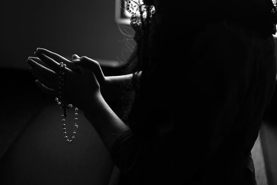 silhouette of woman holding rosary while praying, woman praying in the room