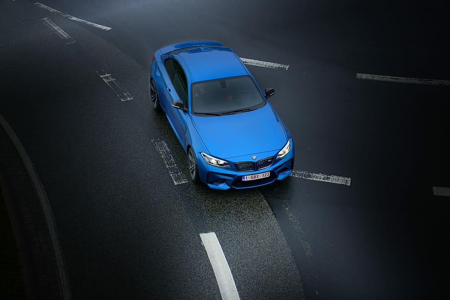 aerial photography of blue sedan on highway, blue BMW car traveling black asphalt road