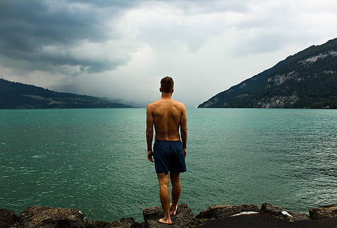 man in black short standing on rock beside lake, men, one Person HD wallpaper
