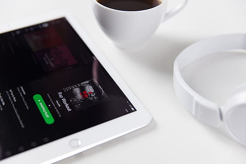 White iPad tablet computer alongside music headphones and coffee HD wallpaper