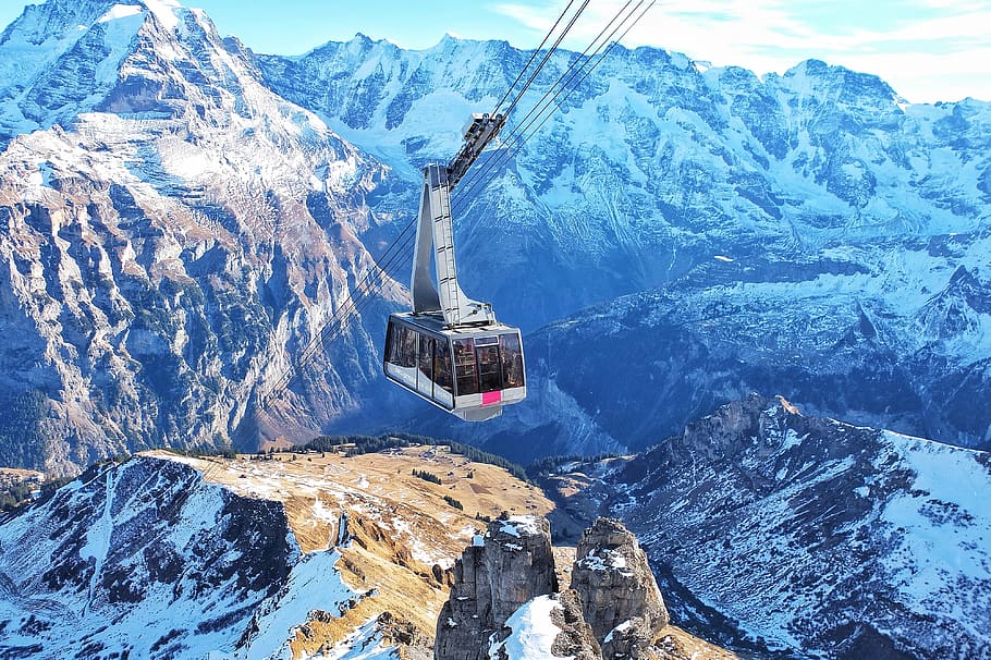 bird's eye view of ski lift over mountains during winter, photo of white and gray cable cart with snow capped mountain