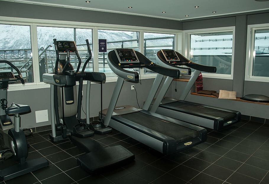 two gray-and-black treadmill besides of black and gray elliptical trainers