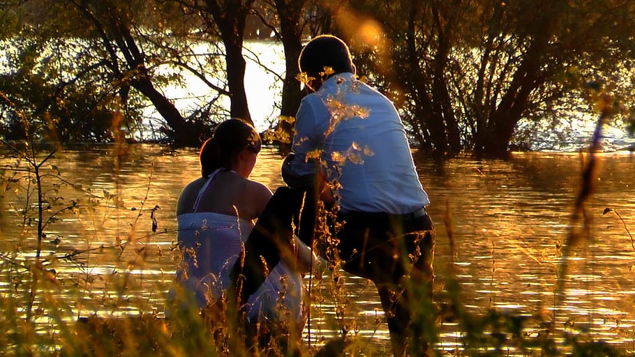 woman sitting beside man near body of water, lovers, abendstimmung HD wallpaper