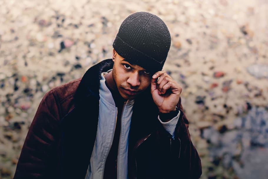 selective focus photo of man wearing brown coat and beanie, man holding black beanie HD wallpaper