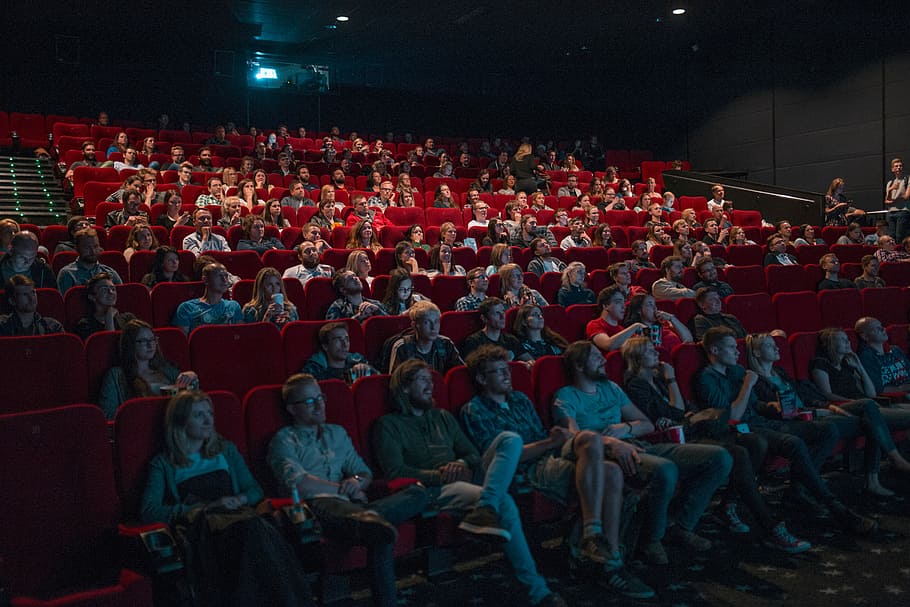 person watching movie, people sitting on chair inside room, cinema