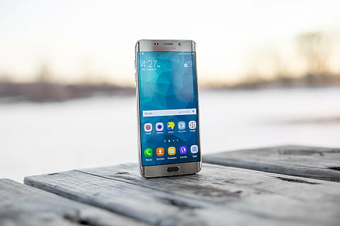 silver Samsung Galaxy Android smartphone on top of gray wooden table HD wallpaper