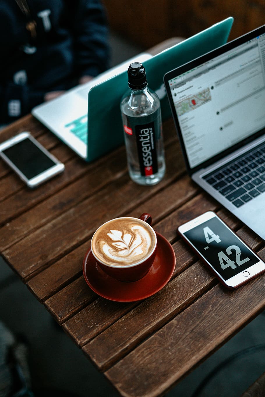 cappuccino on table beside iPhone, flatlay photo of coffee art latte in red ceramic mug near iPhone and MacBook Pro HD wallpaper