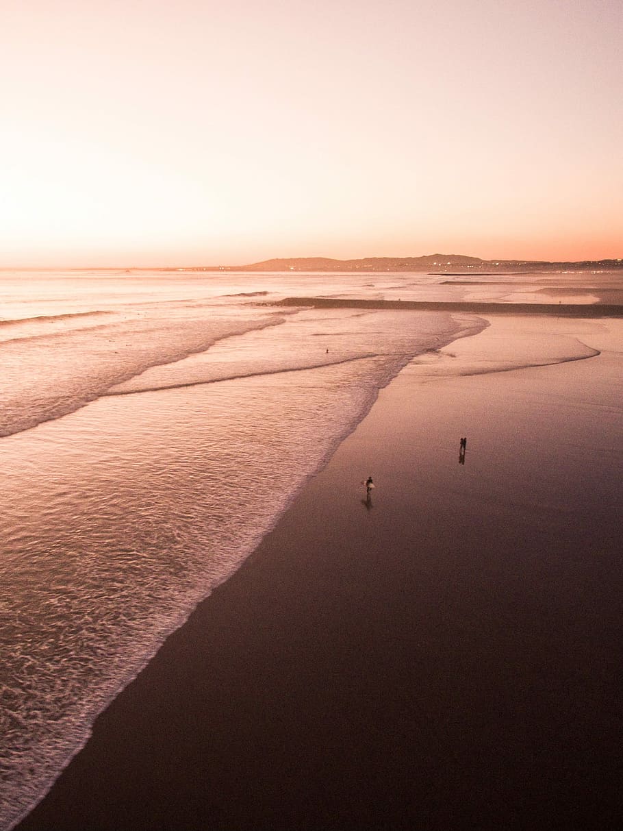 Summer ending, two person standing on seashore under yellowish sky HD wallpaper