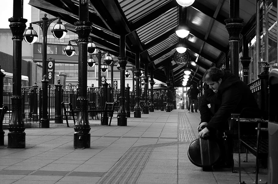 grayscale photo of man sitting down on bench outside building HD wallpaper