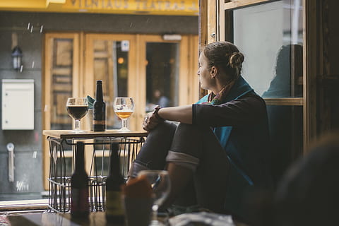 sitting woman in front of table with wine glass and glass bottle HD wallpaper