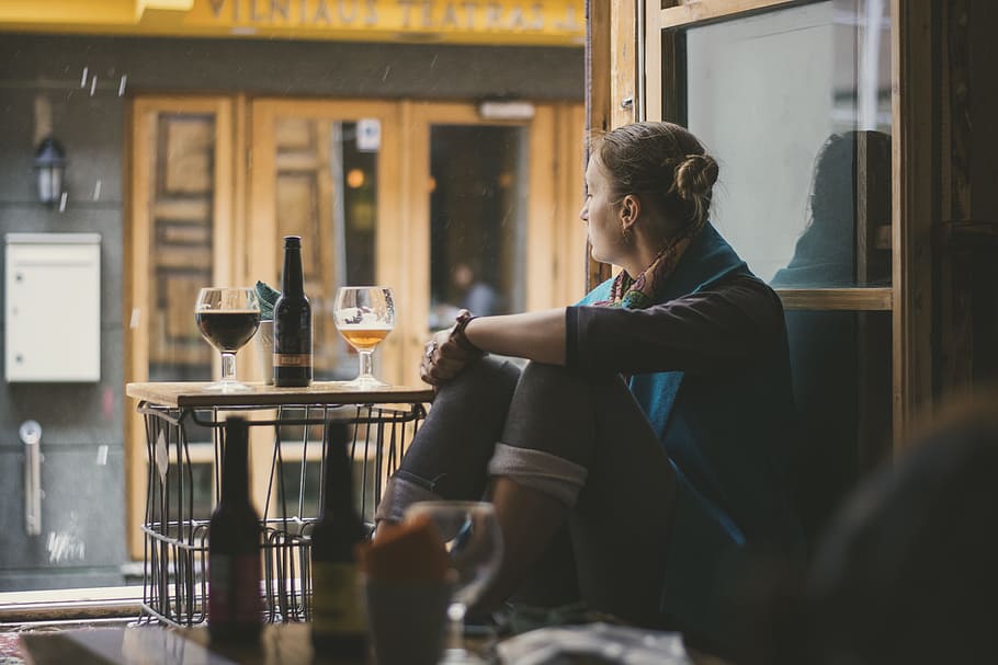 sitting woman in front of table with wine glass and glass bottle HD wallpaper