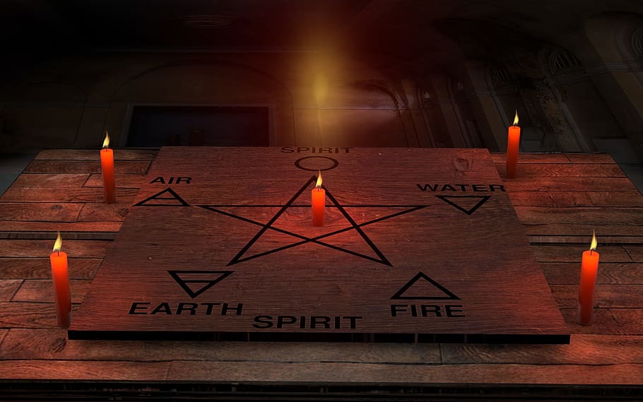 six element and star draw on board beside four candles, space