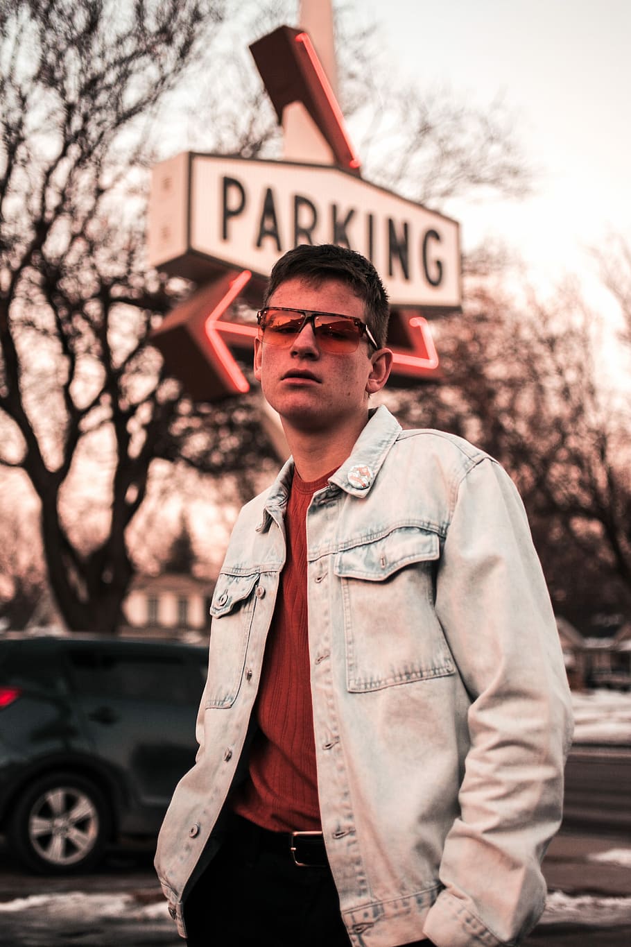 man standing in front of parking signage, man wearing blue denim jacket standing near the parking signage HD wallpaper