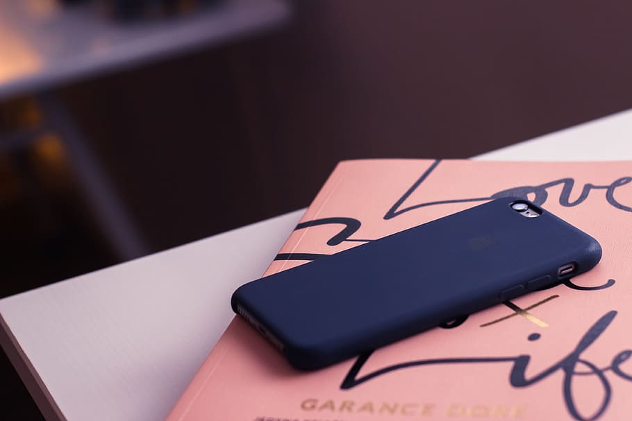 black silicone case smartphone on orange and black labeled book HD wallpaper