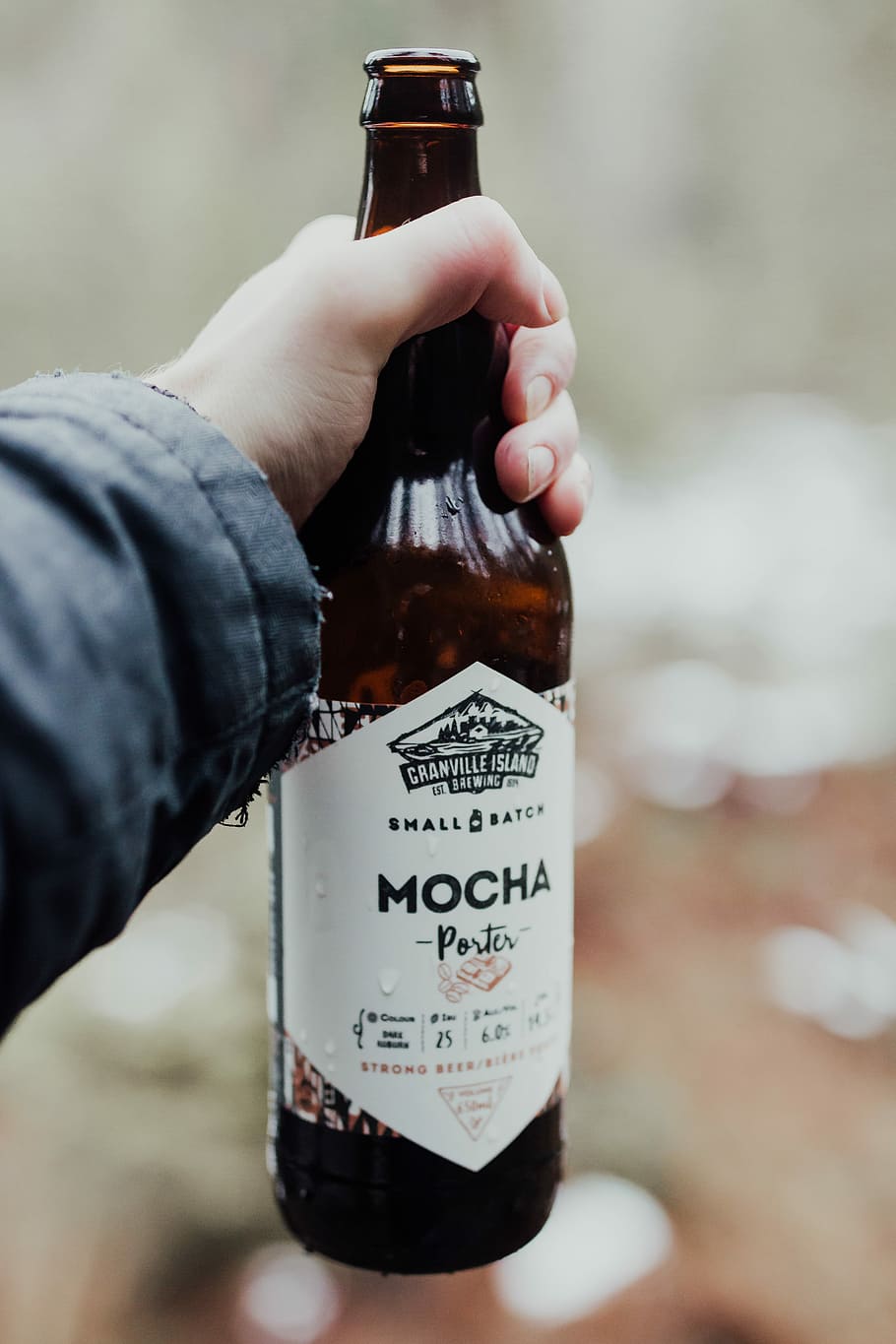 person holding Mocha porter beer bottle, selective focus photography of person holding Mocha Porter glass bottle HD wallpaper