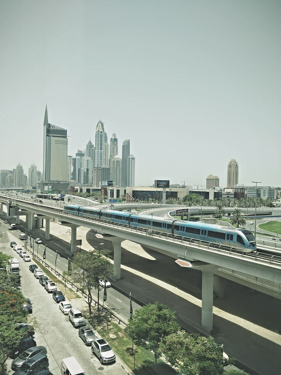 blue train near high-rise buildings under gray sky at daytime, blue and black train on railway HD wallpaper