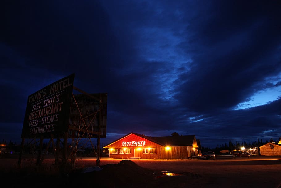 black signage near lighted house during nighttime, brown and black house under clear blue sky during nighttime HD wallpaper