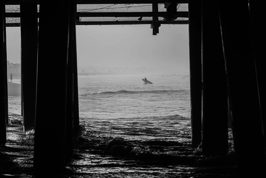 grayscale photo of dock and body of water, gray scale photography of person holding surfboard HD wallpaper