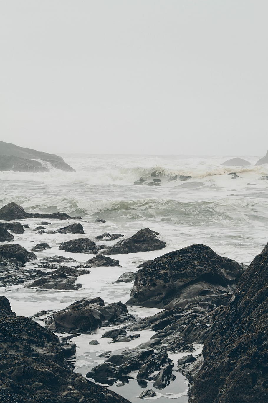 black rock formation near body of water under white sky, photo of sea waves beside rocks during daytime HD wallpaper