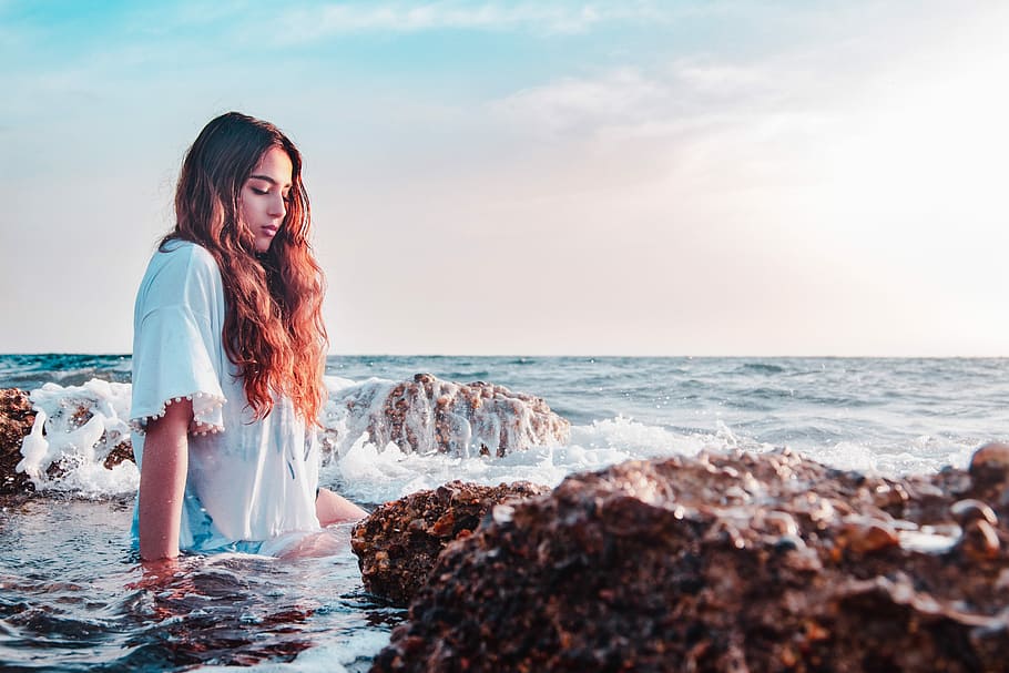 woman sitting at the rocky shore, woman sitting on seashore beside stones, HD wallpaper