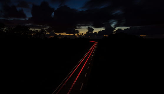 time lapse photography of vehicle light, red and gray roadway between trees HD wallpaper