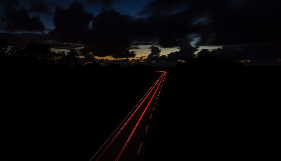 time lapse photography of vehicle light, red and gray roadway between trees HD wallpaper