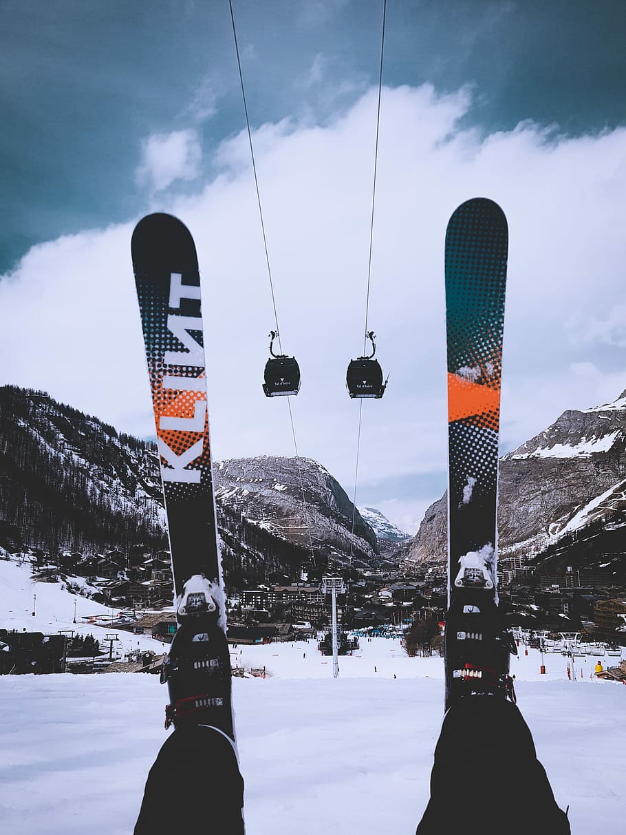 person sitting on snow wearing snow skis, person wearing green-and-orange snow skis HD wallpaper