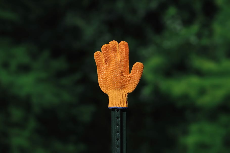 shallow focus of left orange knitted glove, black metal stick with orange glove