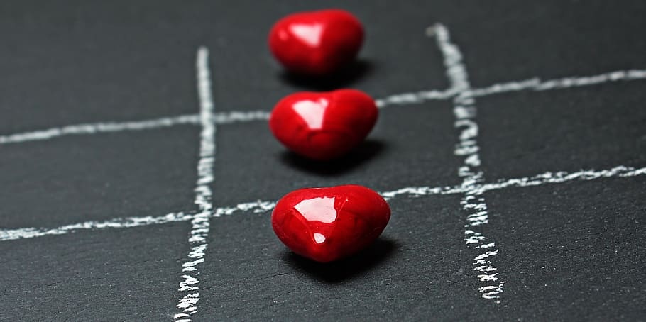close up photo of three heart-shaped red stones, tic tac toe