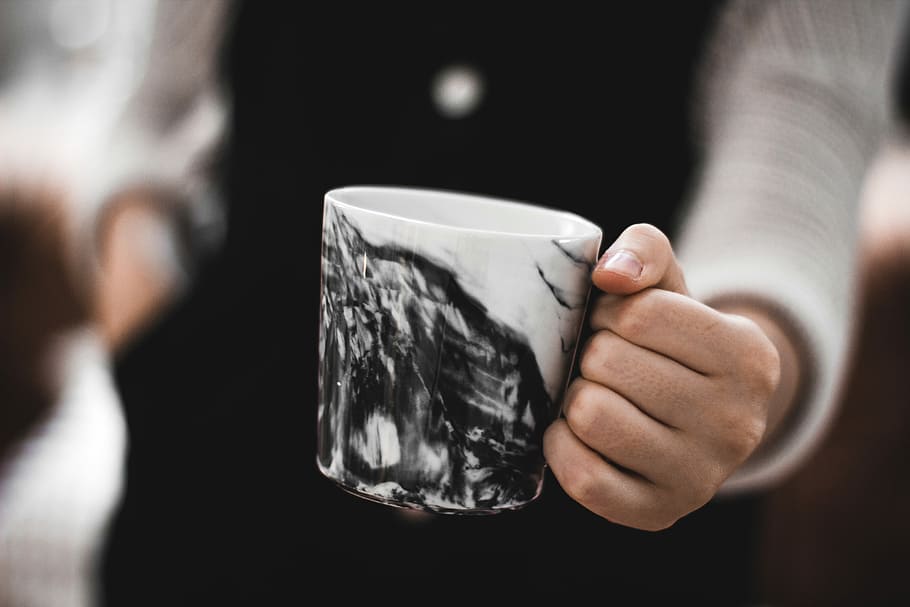 person holding a white and black ceramic mug, focus photography of black and white mountain-printed mug HD wallpaper