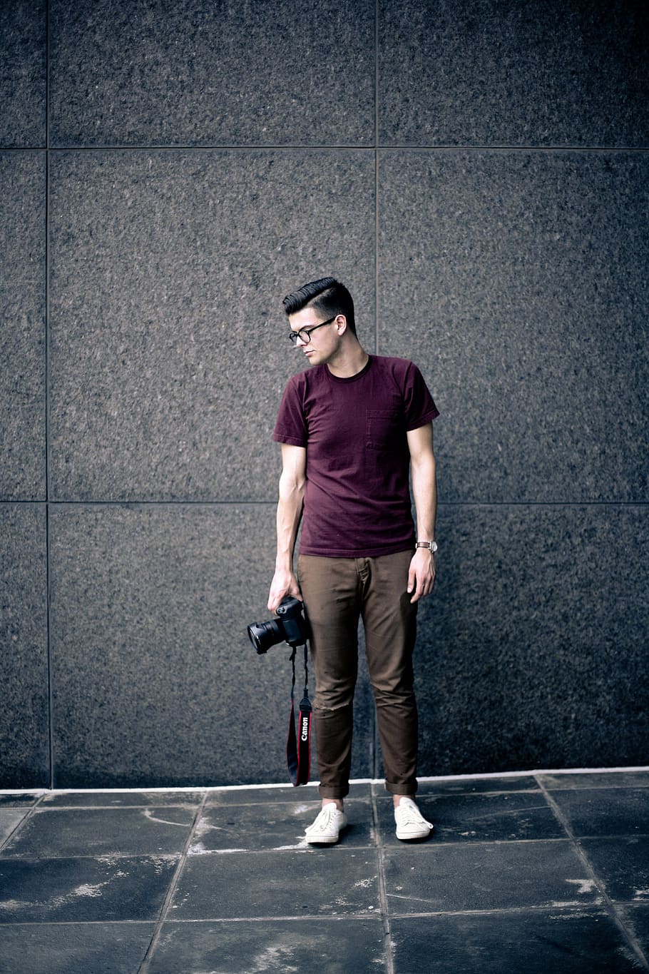 man in maroon crew-neck t-shirt holding Canon DSLR camera standing on the wall, HD wallpaper