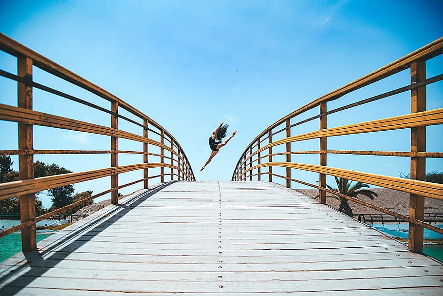 woman jumping near bridge during daytime, photo of woman leaping on bridge HD wallpaper